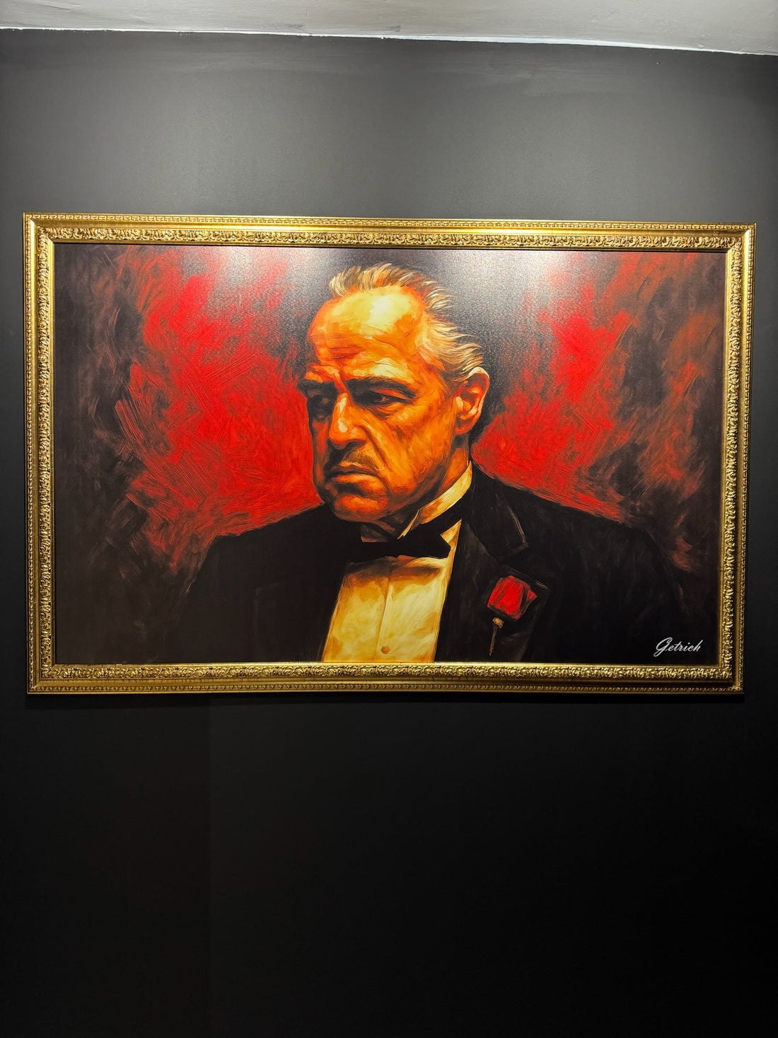 Framed painting of a man with a red background on a dark wall