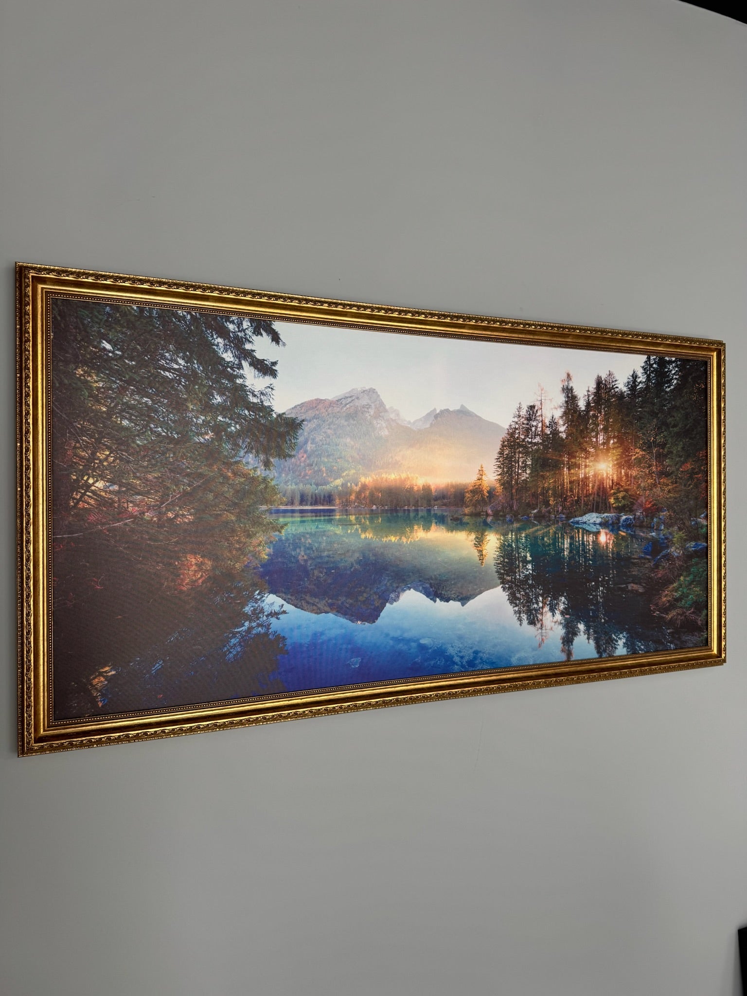 Framed photograph of a mountain landscape with a lake on a white wall.