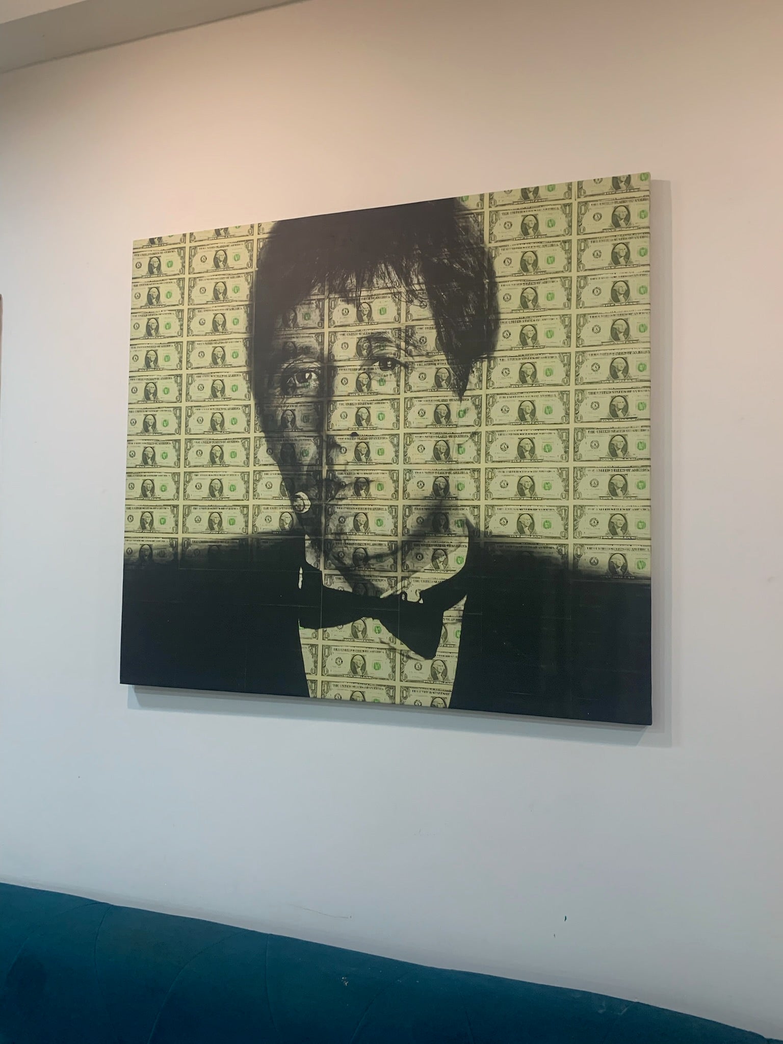 Framed portrait of a person with a dollar bill pattern on the wall behind