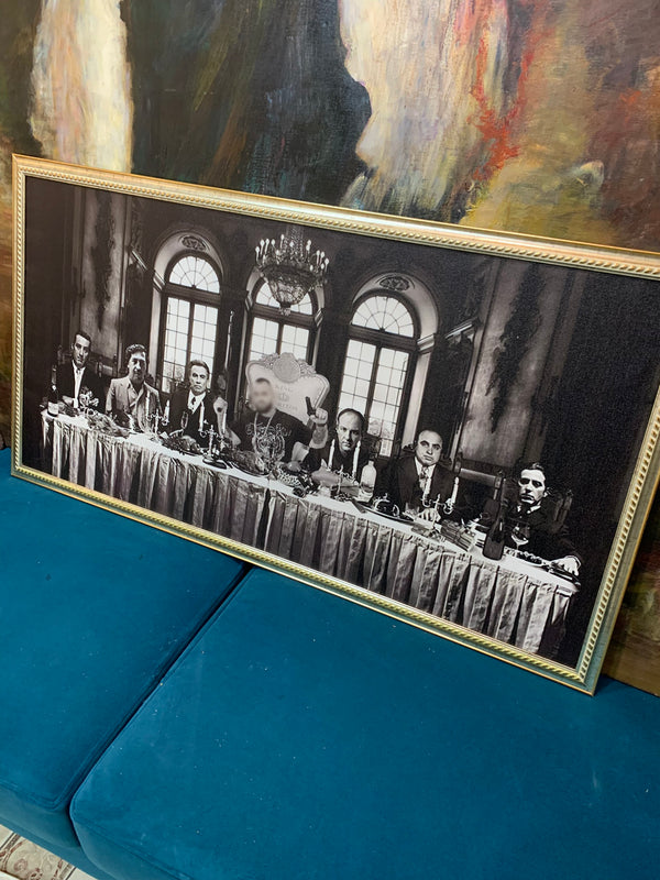Framed black and white photograph of a formal gathering with people seated at a long table.
