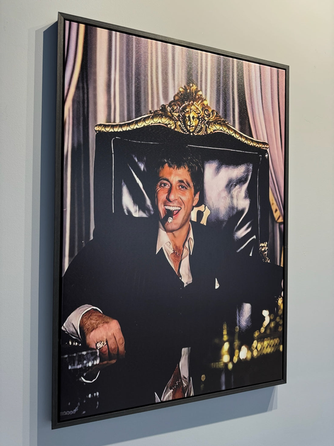Framed picture of a person sitting in an ornate chair with decorative elements.