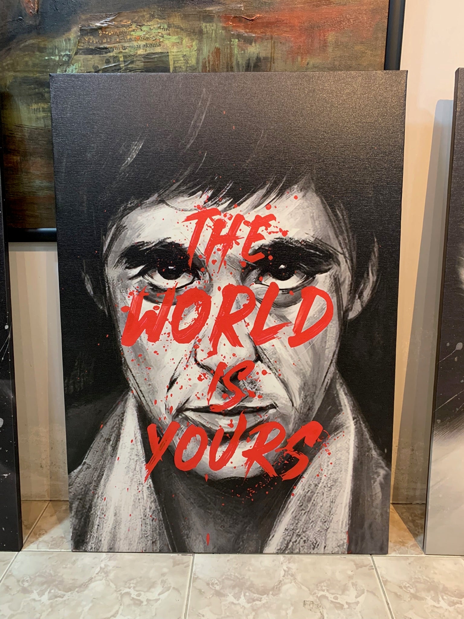 Canvas print with a stylized portrait and 'The World is Yours' text, displayed indoors.