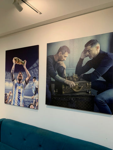 Two large wall art prints of athletes on a white wall above a teal couch.