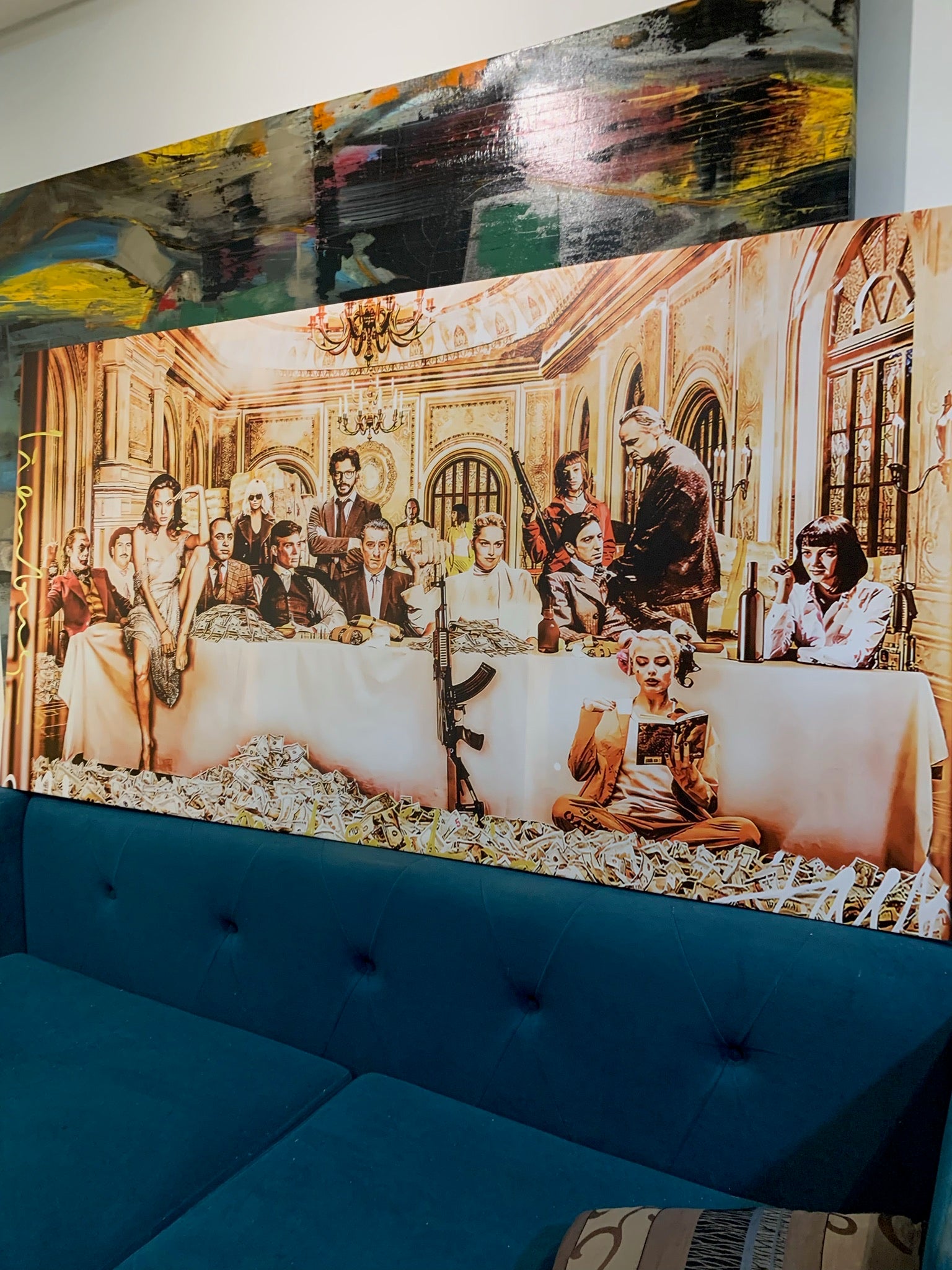 Blue sofa with a decorative headboard featuring a painting of a formal dinner scene.