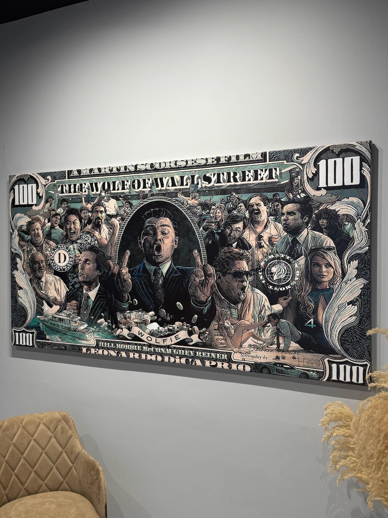 Framed artwork of a group of people on a wall, resembling a large dollar bill.
