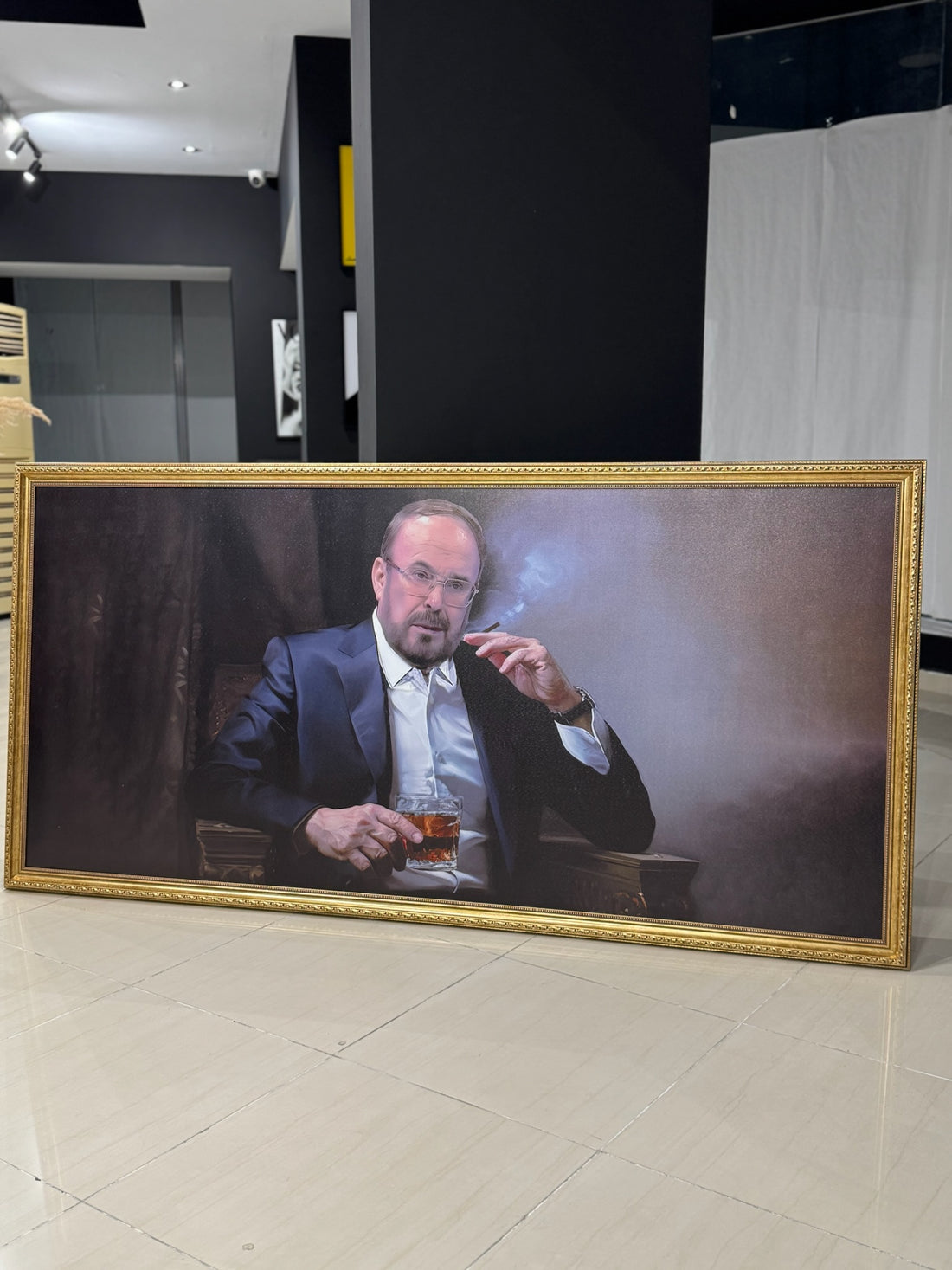 Fatos Nano. Framed portrait of a man smoking a cigarette and holding a drink on a wall.