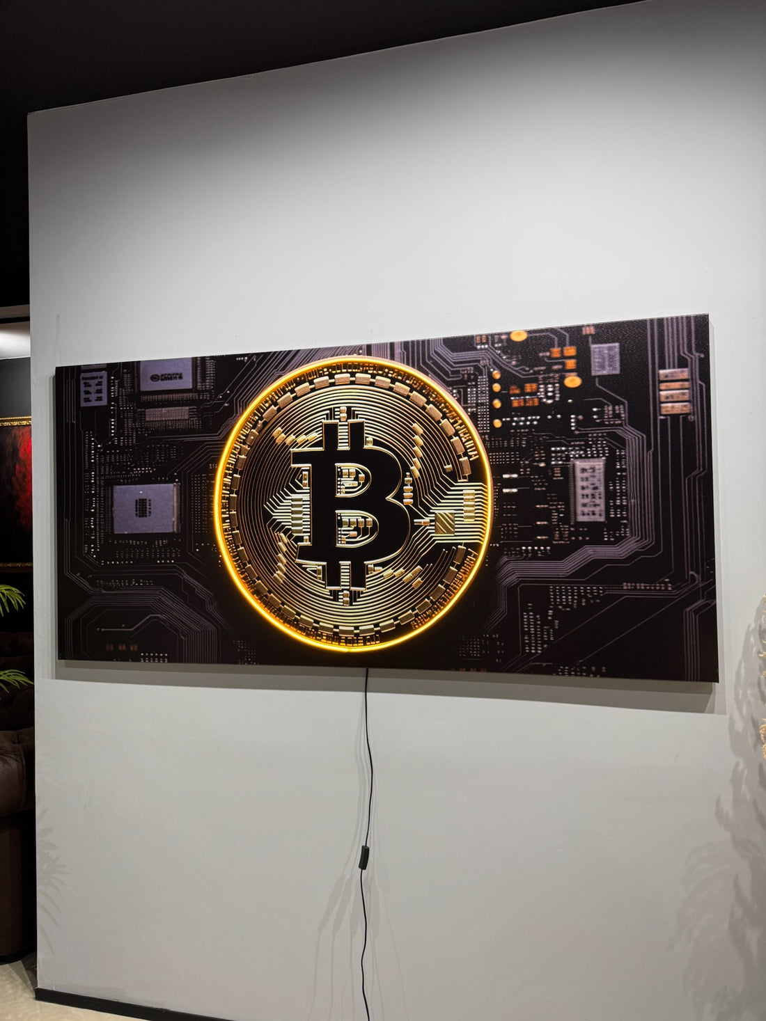 Decorative wall art with Bitcoin symbol on a black background in a modern interior setting.