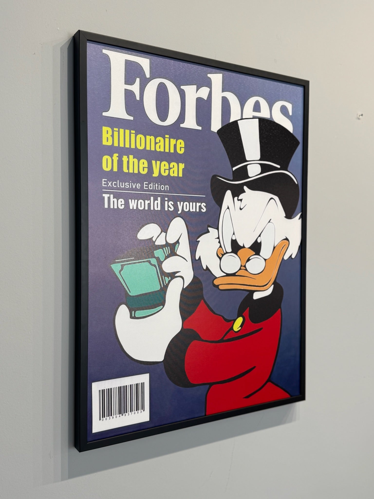 Framed poster of a cartoon character holding money with 'Forbes' branding on a gray wall.