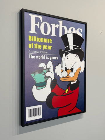 Framed poster of a cartoon character holding money with 'Forbes' branding on a gray wall.