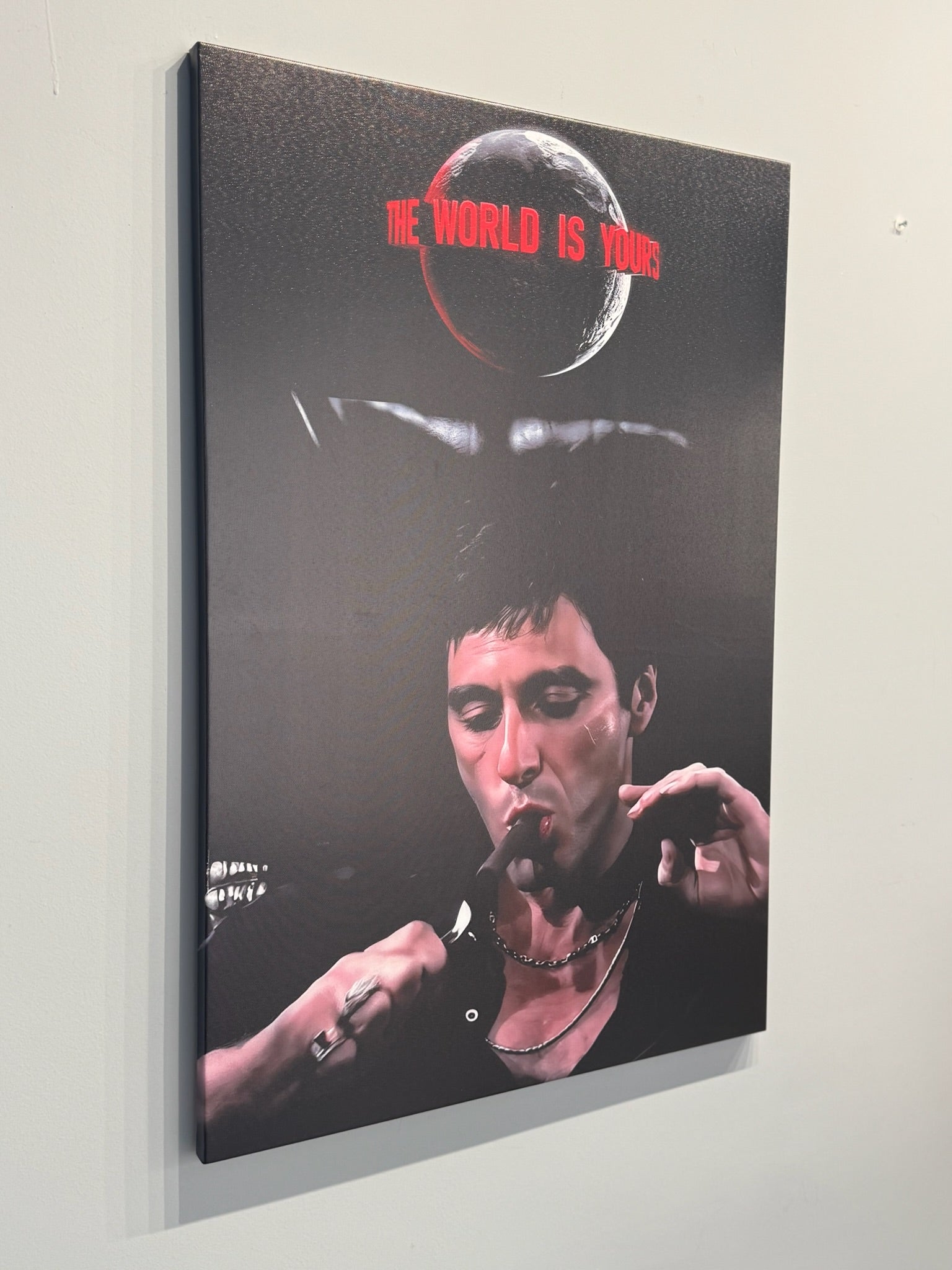 Canvas print of a stylized portrait with text 'The World is Yours' on a plain wall.