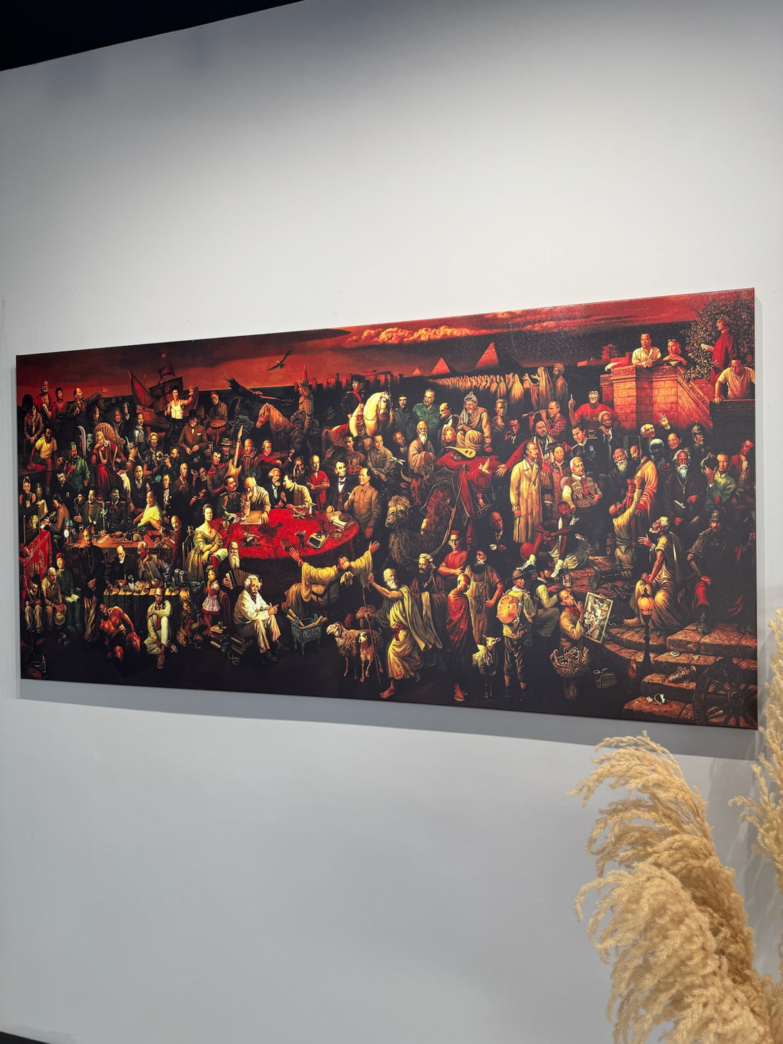 103 Personazhet e historise. Large painting of a crowded room scene on a white wall.