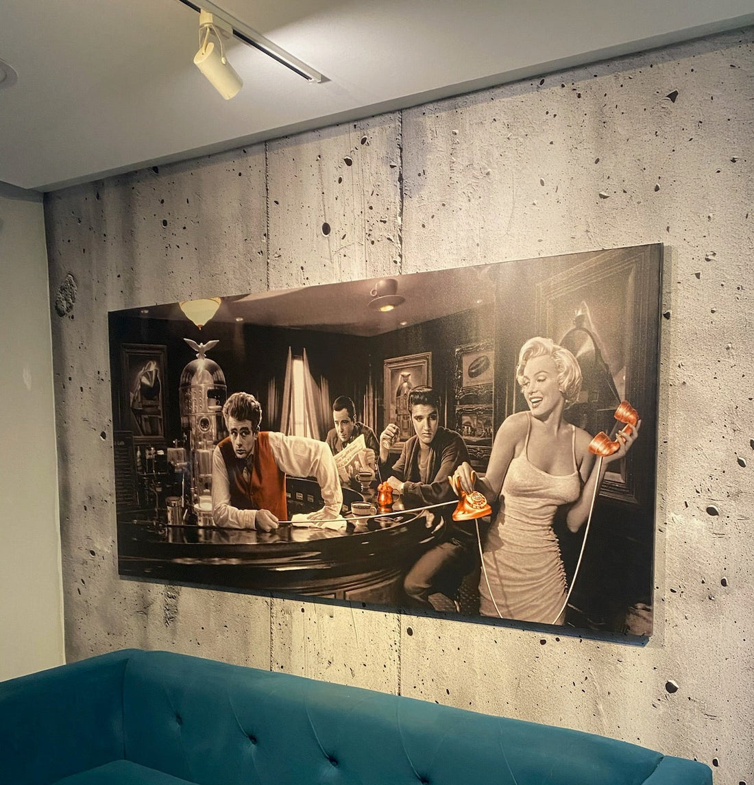 Large framed black and white photograph of a scene with people on a concrete wall above a blue sofa.