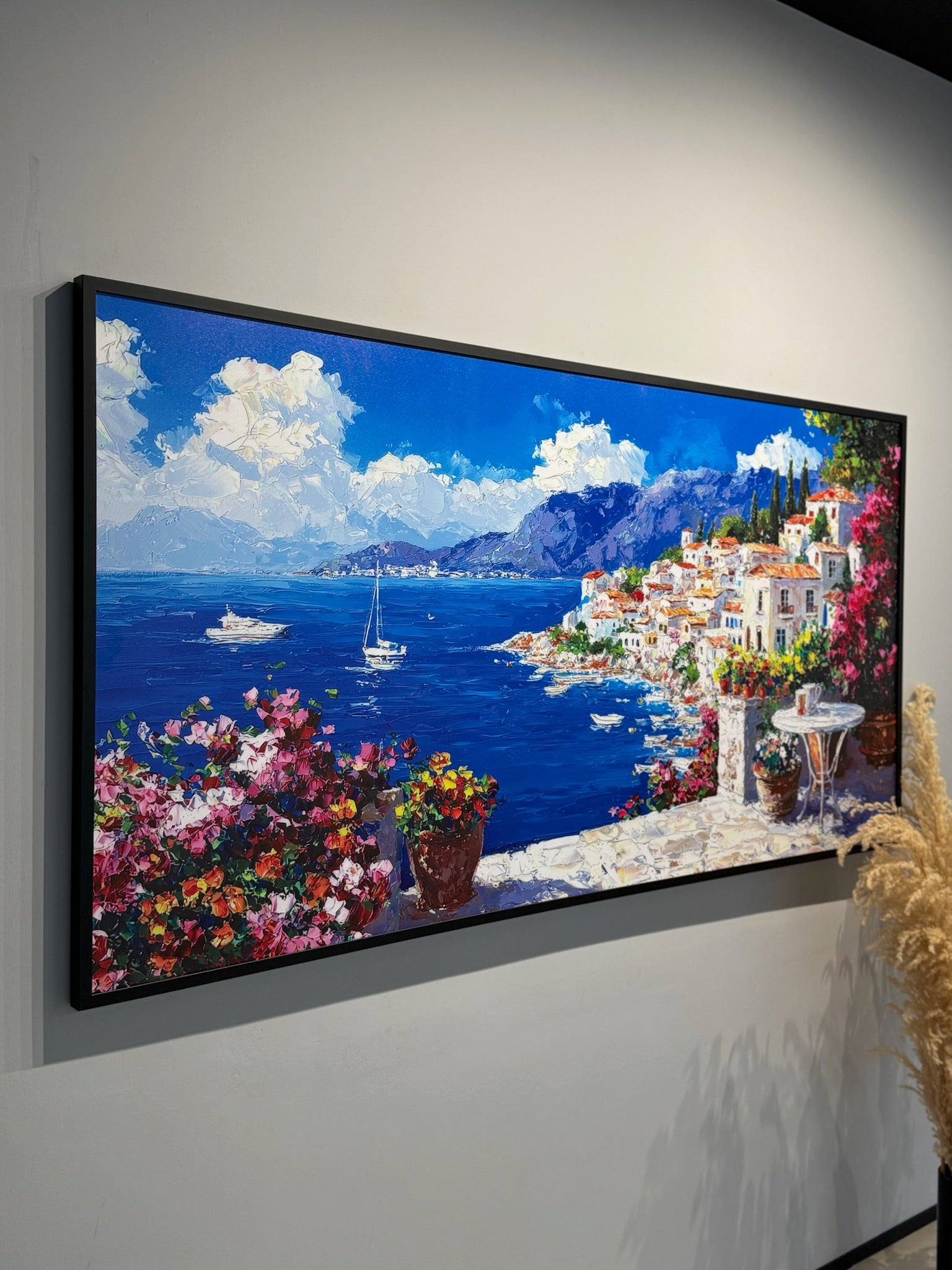 Framed painting of a coastal scene with flowers and buildings.