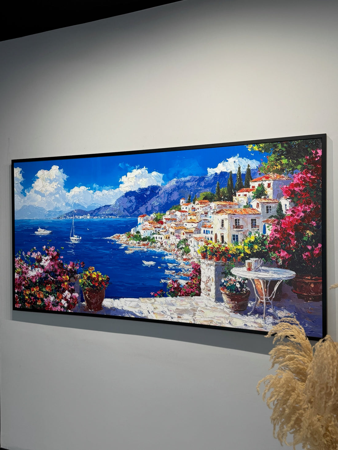 Framed painting of a coastal scene with flowers and buildings.