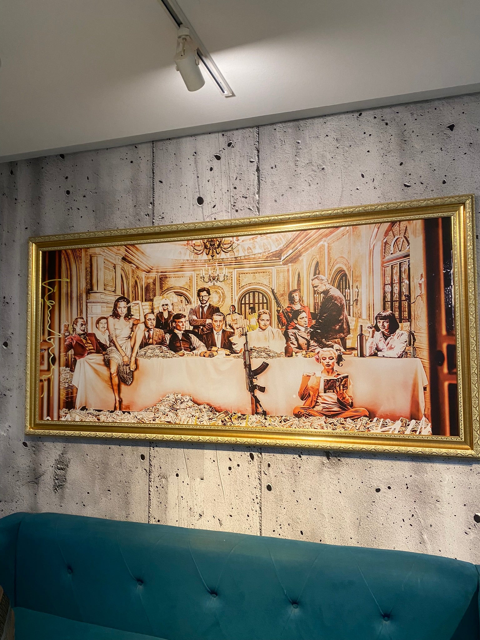 Framed artwork resembling 'The Last Supper' on a textured wall with a blue couch below.