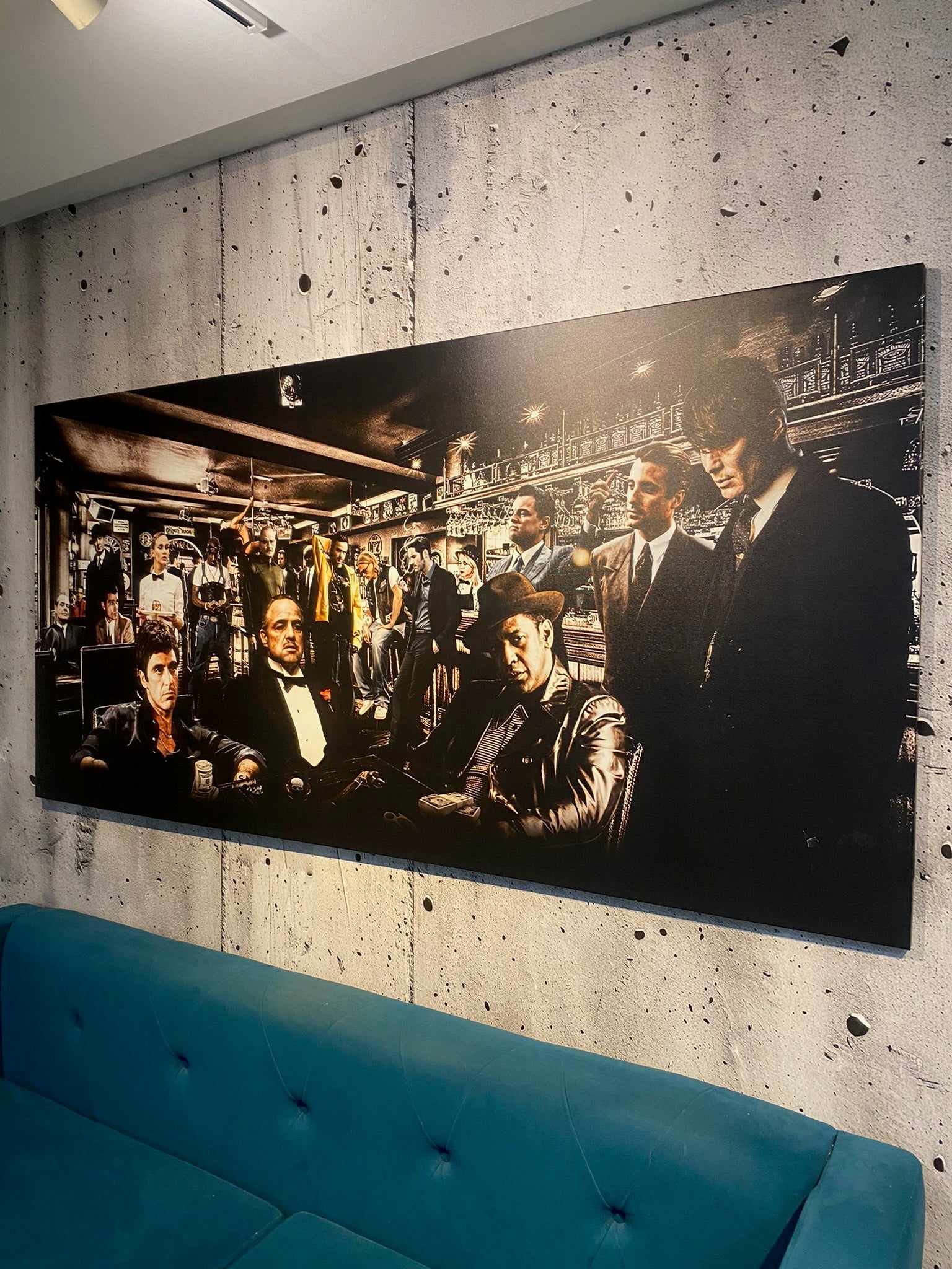 Large black and white mural of a group of people in formal attire on a textured wall above a blue sofa.
