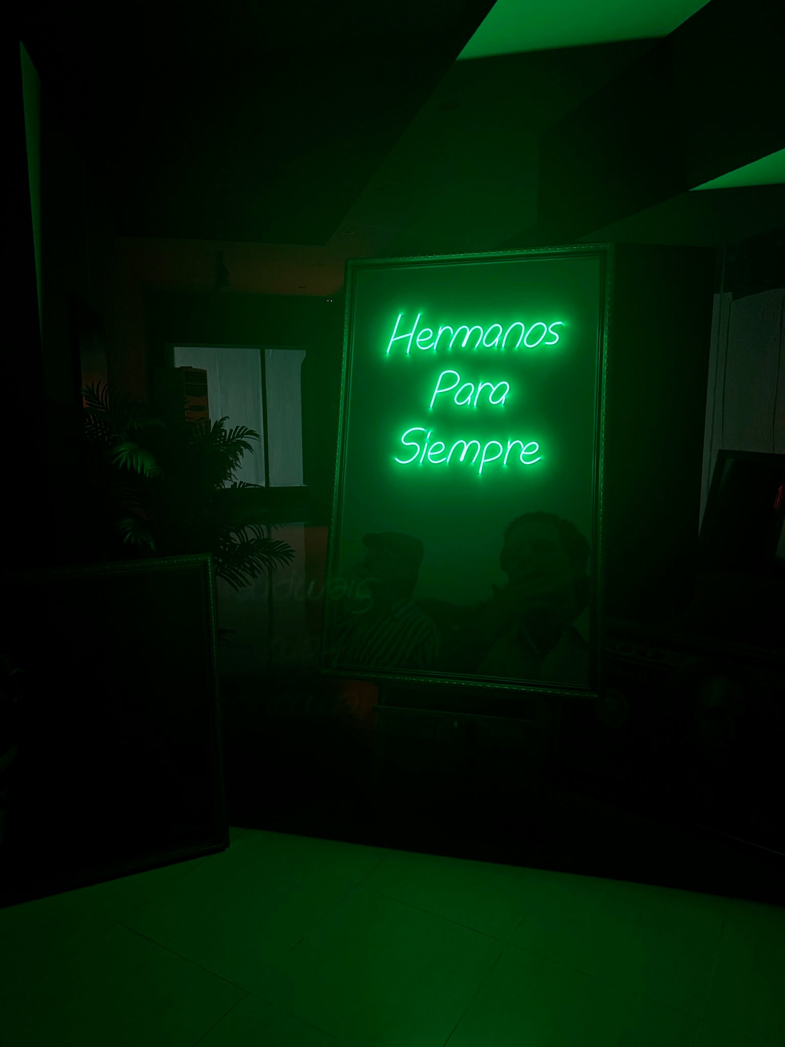 Neon sign with Spanish text in a dark setting