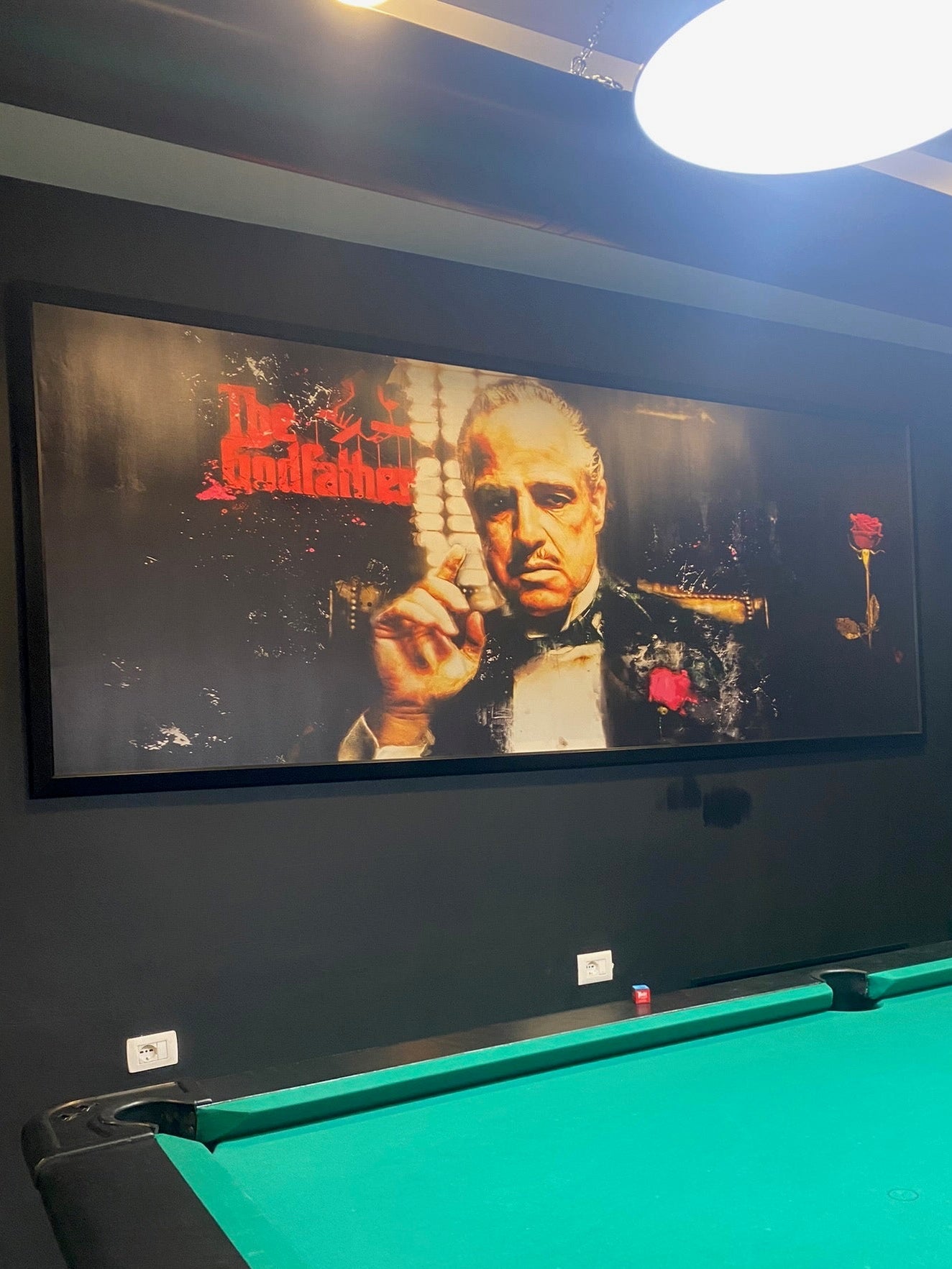 Large screen displaying a movie scene with a pool table in the foreground