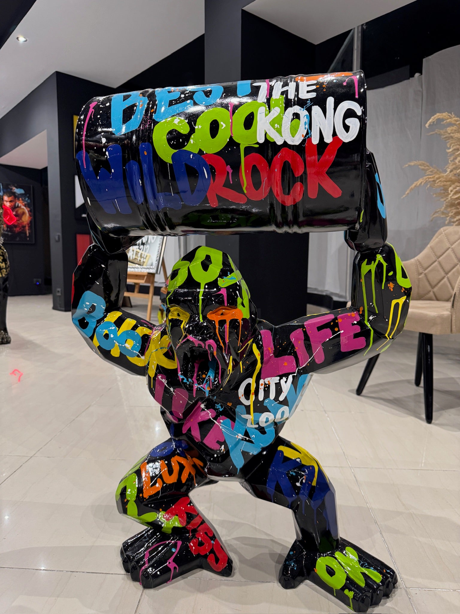 Colorful graffiti gorilla statue holding industrial barrel in modern luxury showroom