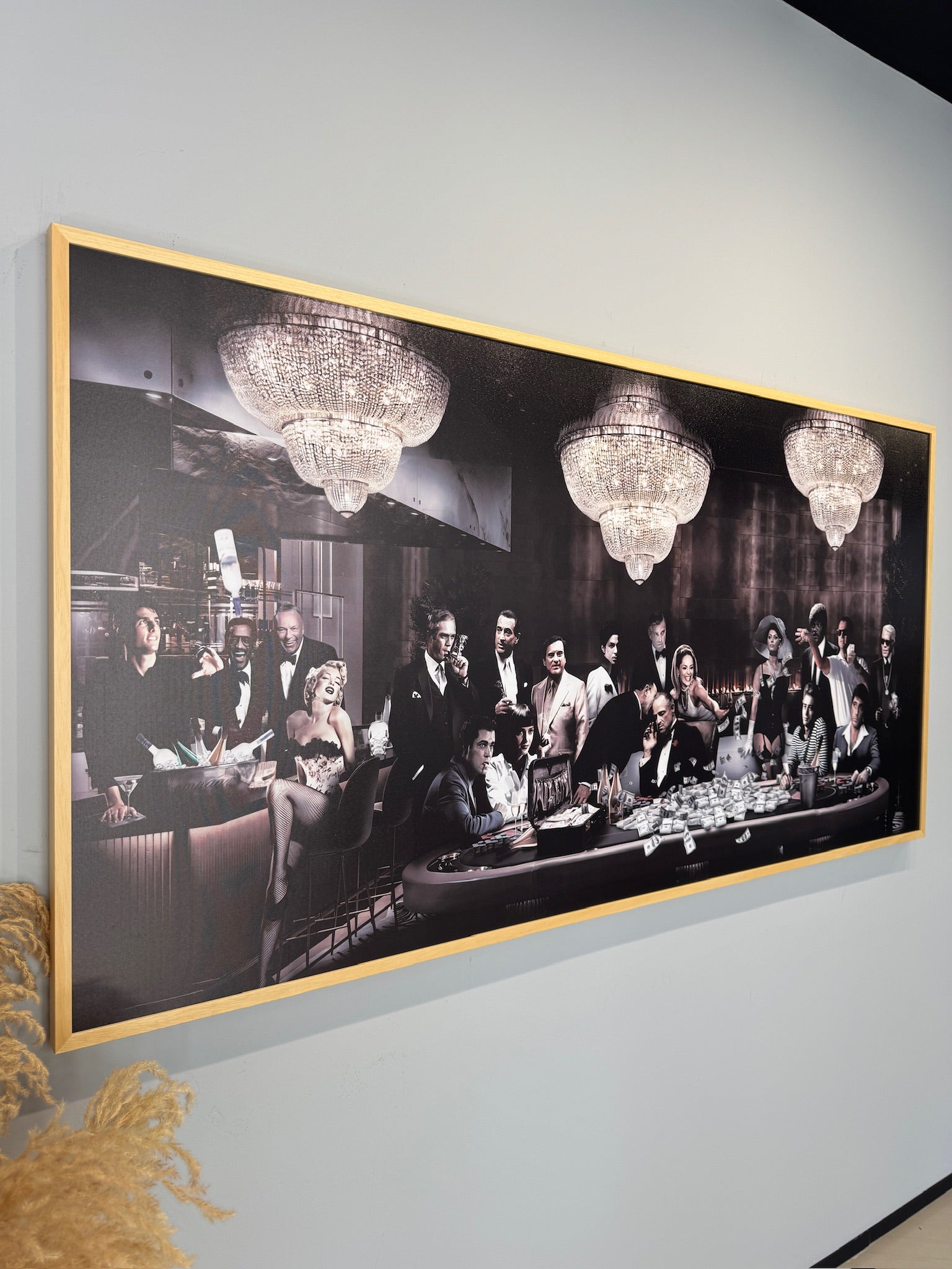 Framed artwork of a glamorous scene with people and chandeliers on a wall.