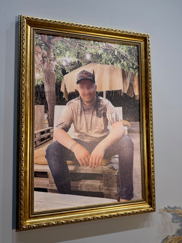 Framed photograph of a person sitting outdoors with a gold frame.