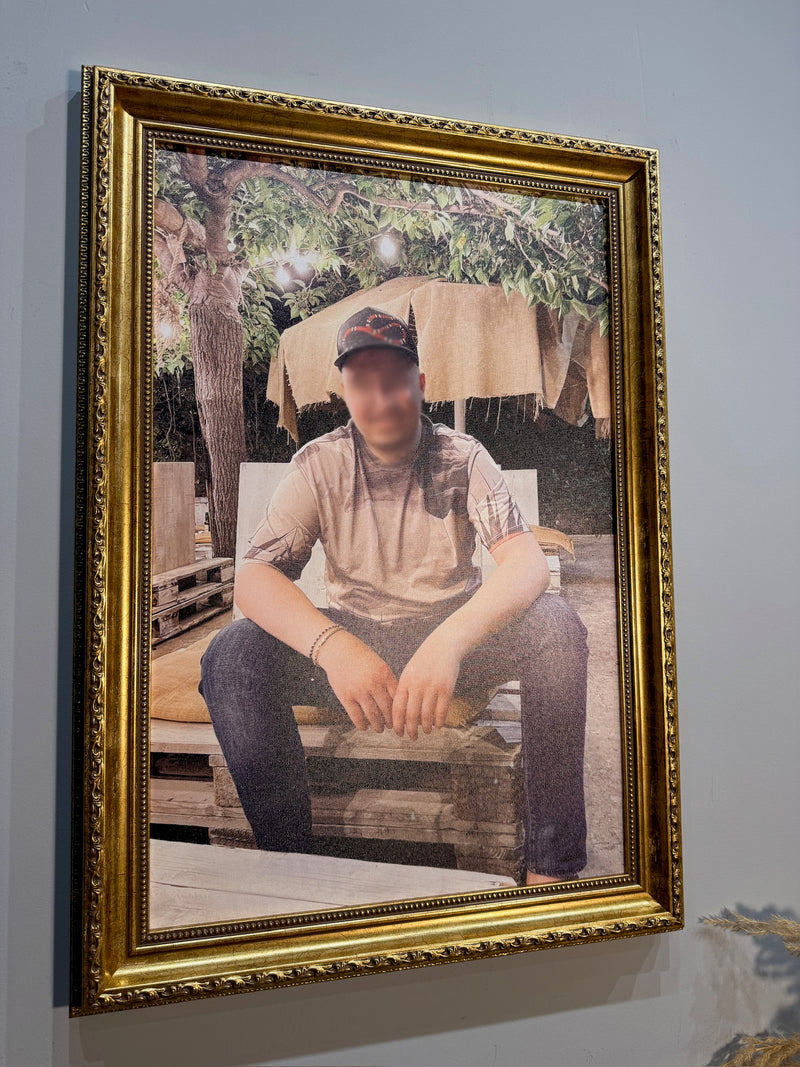 Framed photograph of a person sitting outdoors with a gold frame.