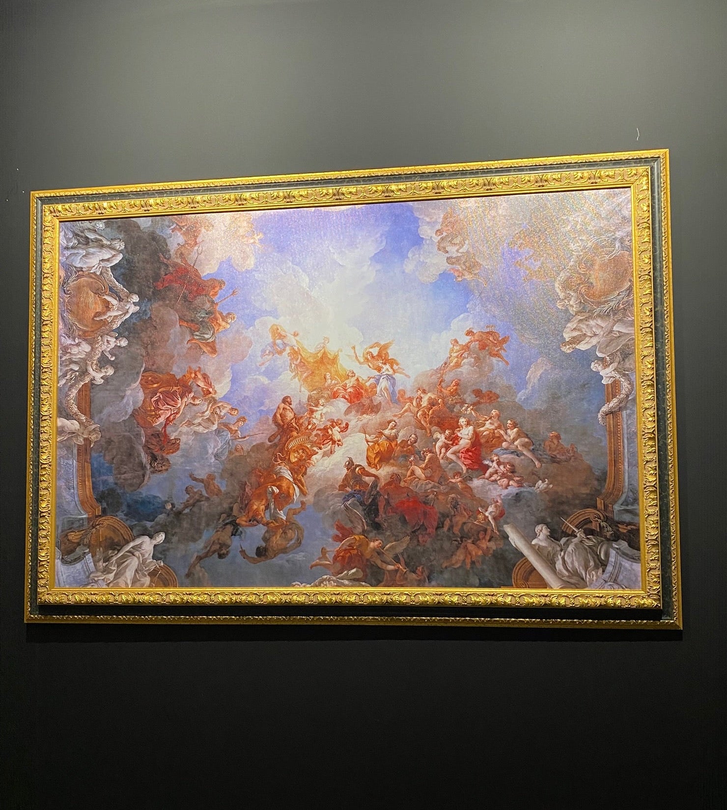 Decorative painting with gold frame on a dark wall