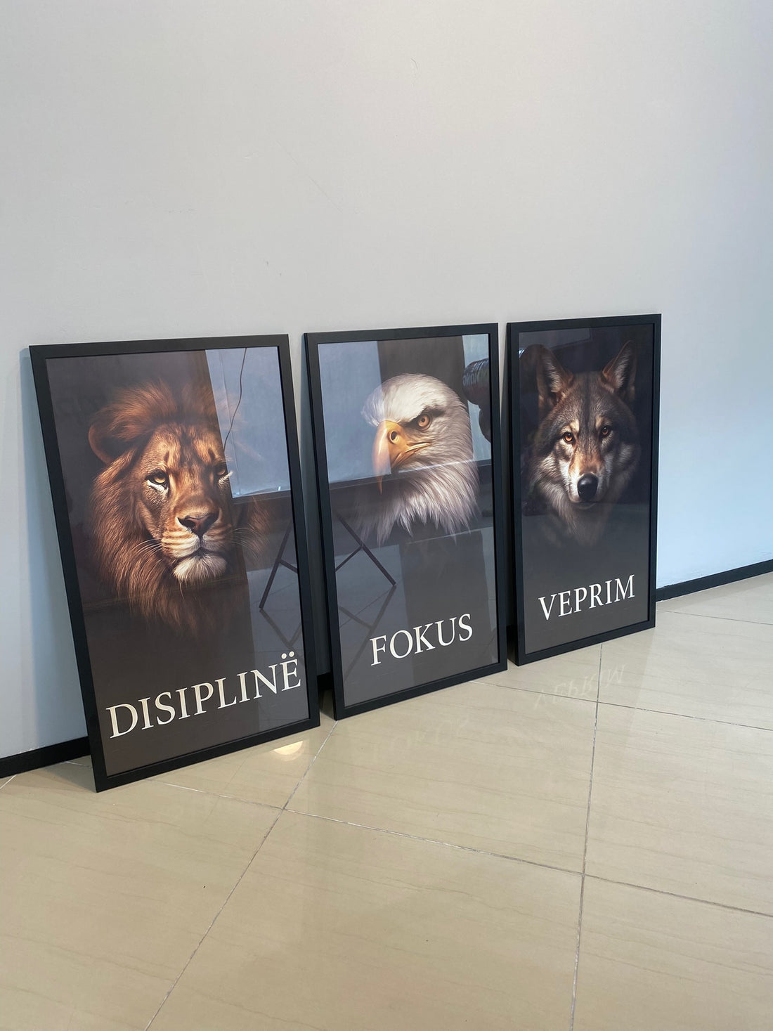 Three framed animal portraits with motivational words on a wall.