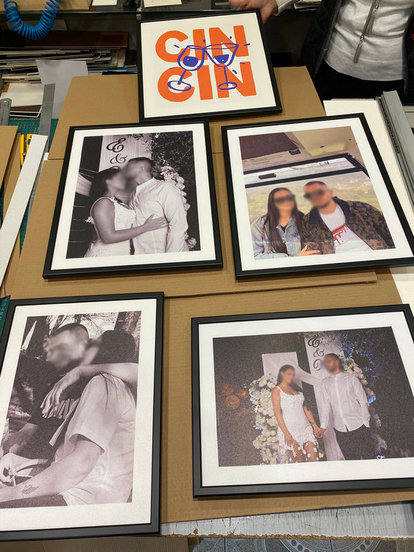 Framed photographs of a couple on a table with a decorative sign above.