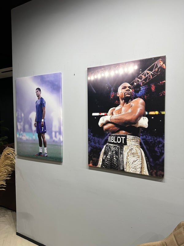 Two large posters of a boxer and a soccer player on a wall.