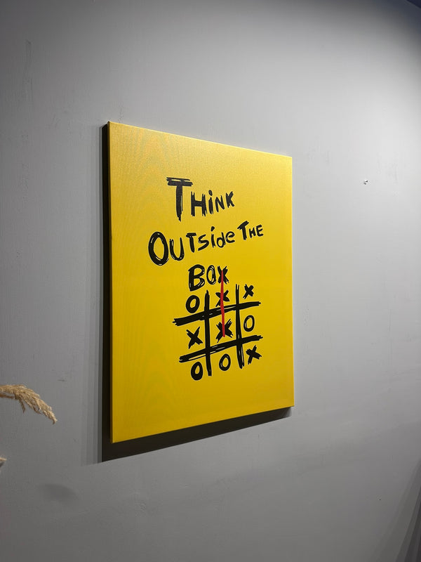 Yellow canvas with 'Think Outside The Box' text and tic-tac-toe game on a gray wall.