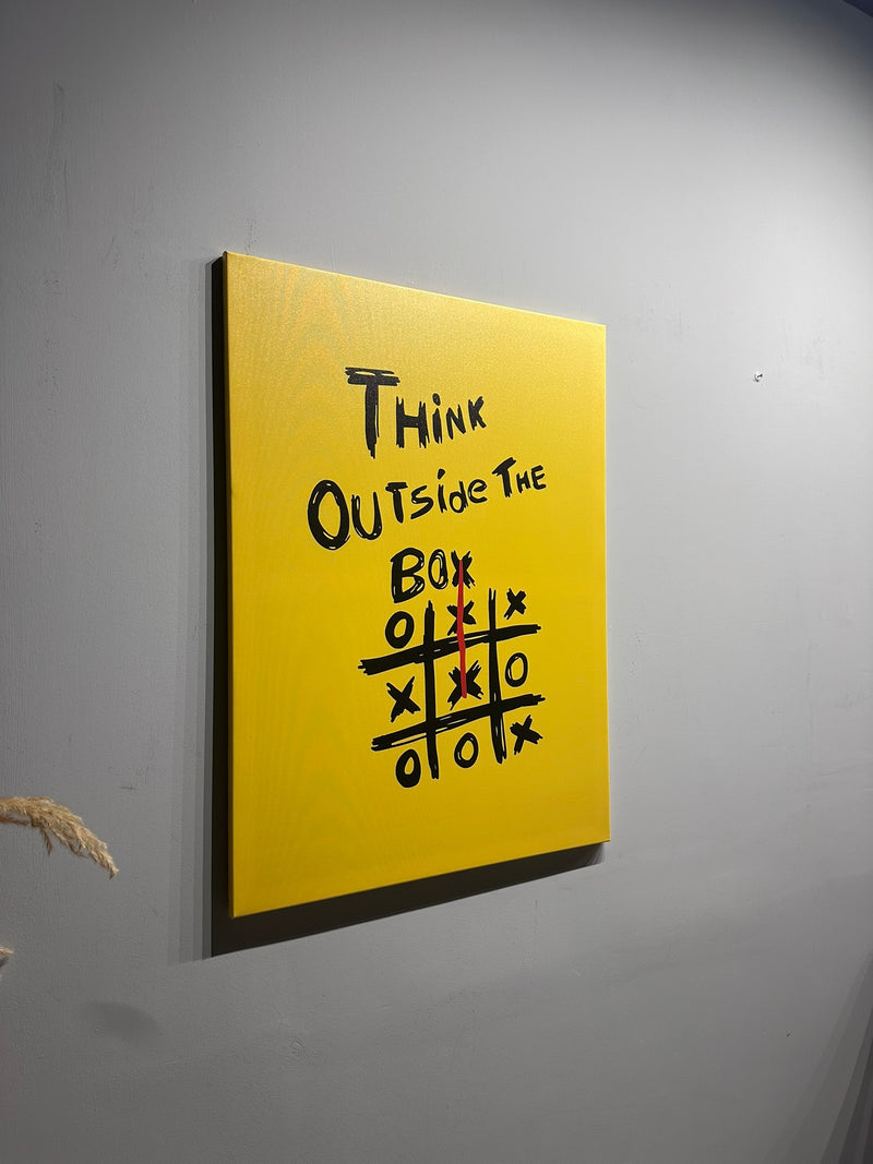 Yellow canvas with 'Think Outside The Box' text and tic-tac-toe game on a gray wall.