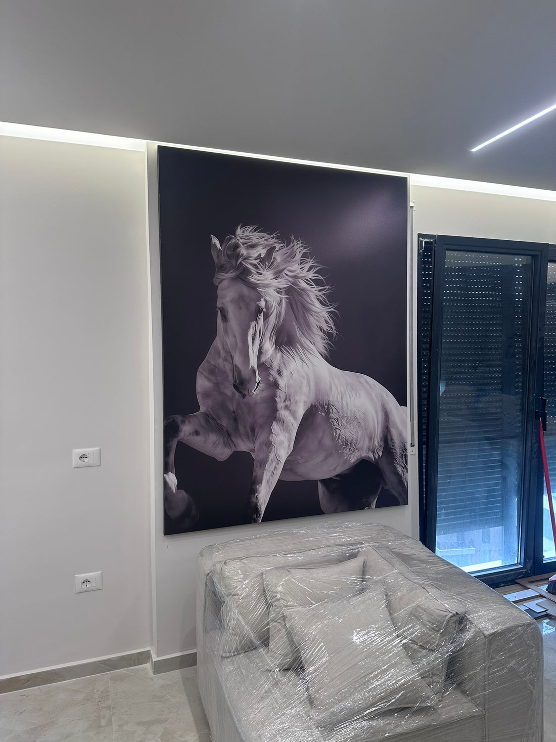 Large wall art of a horse in a room with a plant and chair.