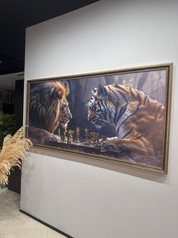 Framed artwork of a lion and tiger playing chess on a wall.