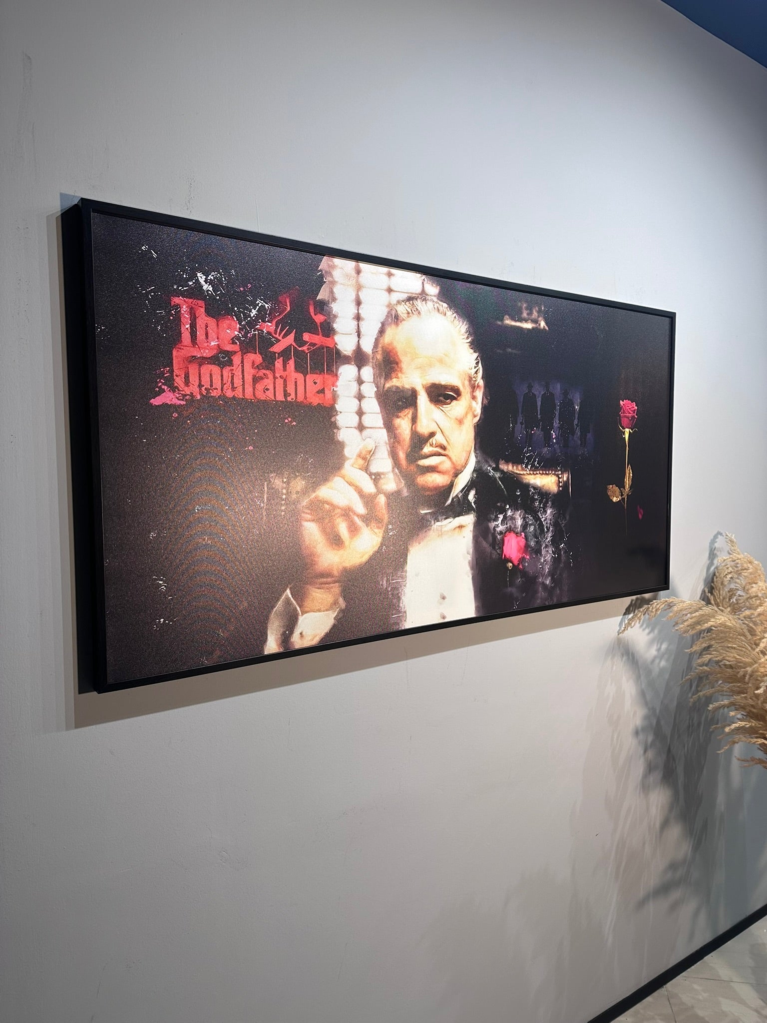 Framed movie poster of 'The Godfather' on a wall.