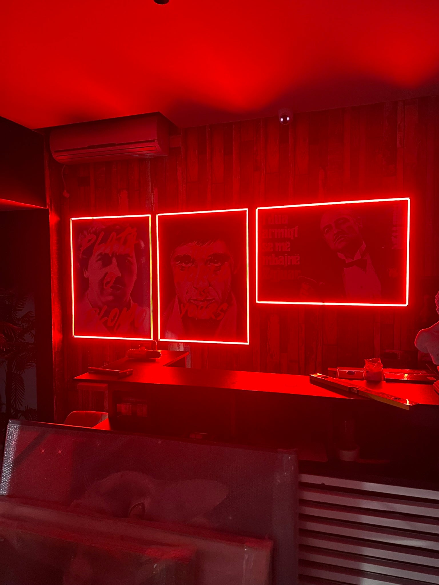 Red-lit room with portraits on the wall and a counter.