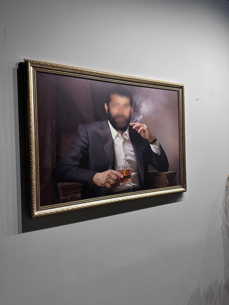 Framed portrait of a man smoking a cigarette and holding a glass on a gray wall.