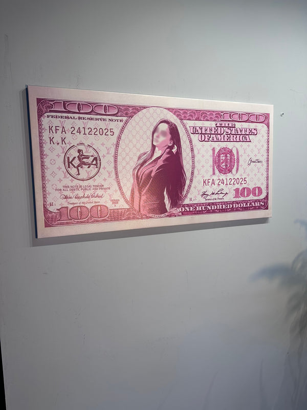 Framed print of a $100 bill with a portrait on a plain wall.