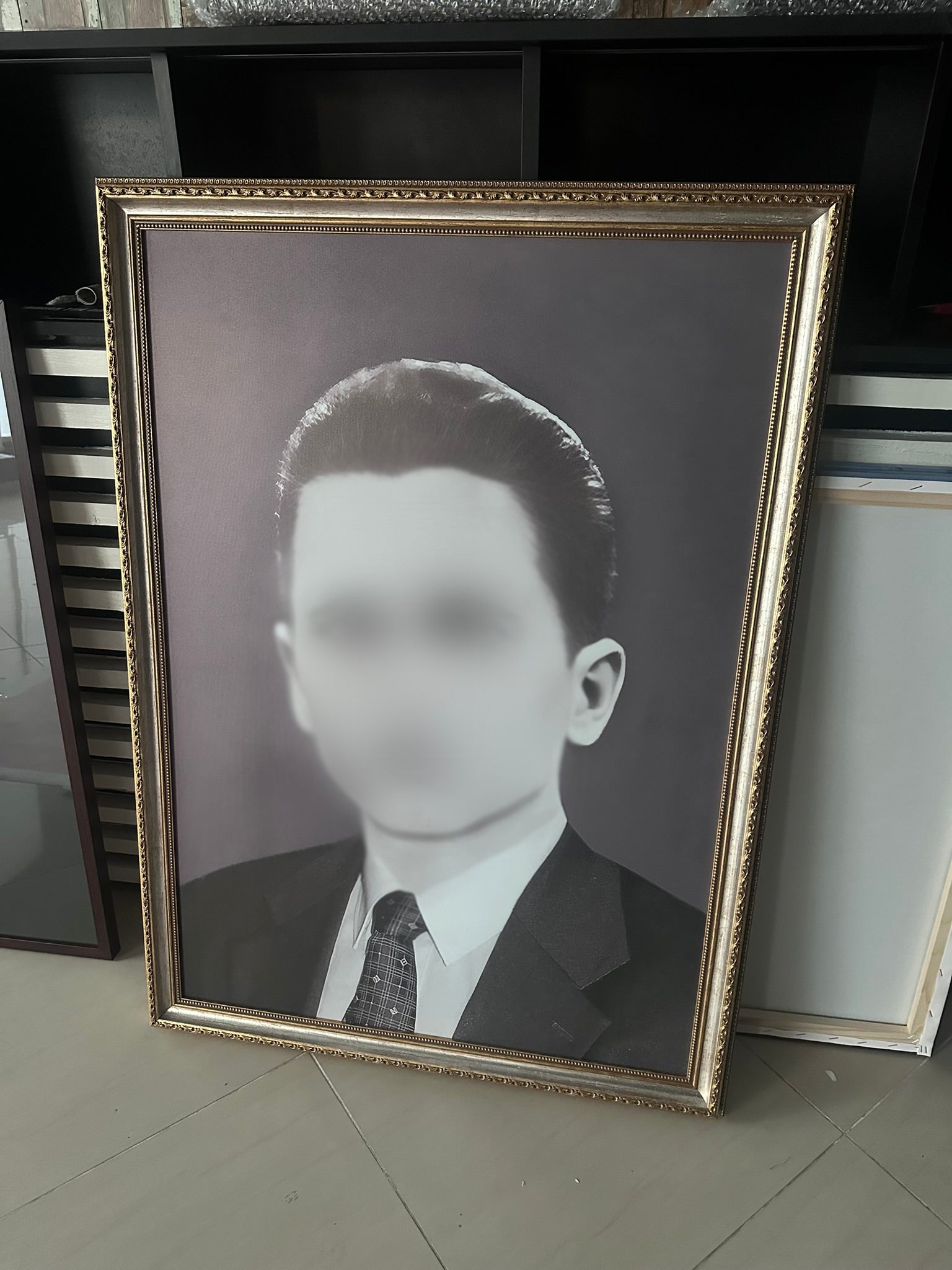 Framed black and white portrait of a man on a tiled floor.