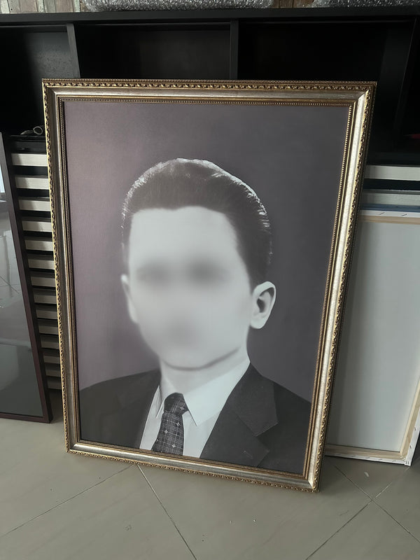 Framed black and white portrait of a man on a tiled floor.