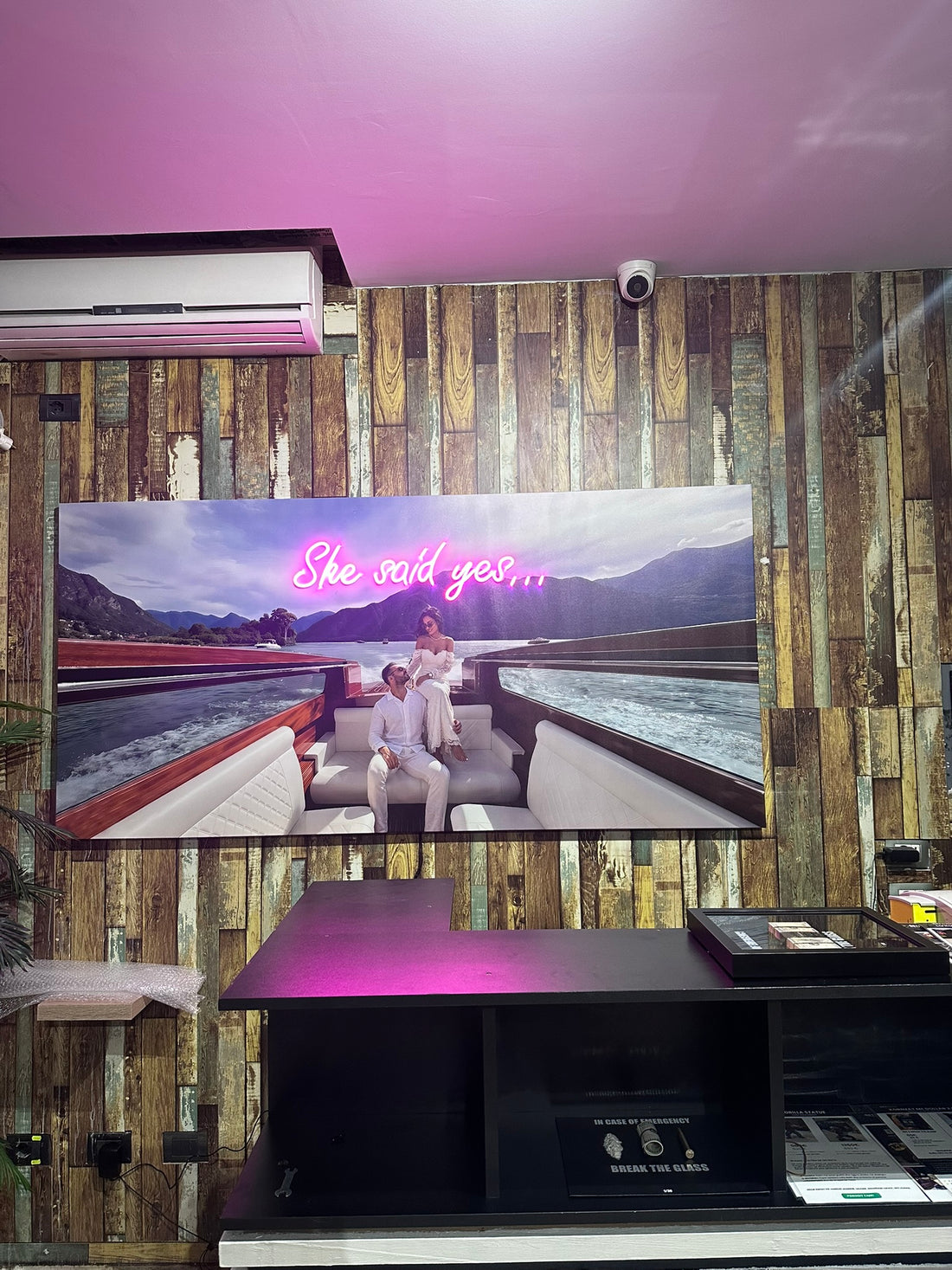Large screen displaying a romantic scene with 'She said yes' text, mounted on a wooden wall.