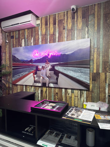 Large screen displaying a romantic scene with 'She said yes' text, mounted on a wooden wall.