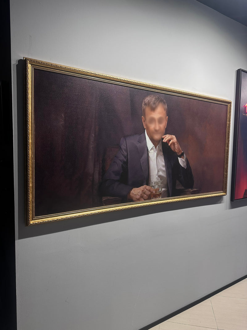 Portrait of a man in a suit with a gold frame on a gray wall.