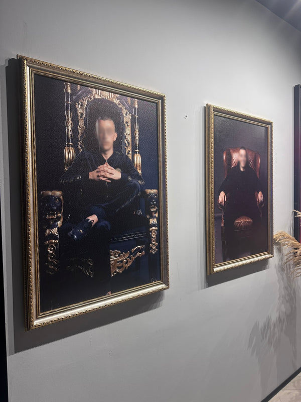 Two framed portraits on a wall with ornate gold frames.