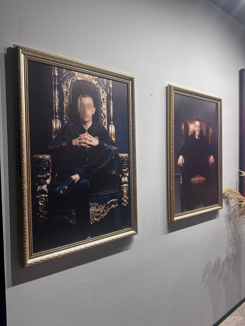 Two framed portraits on a wall with ornate gold frames.