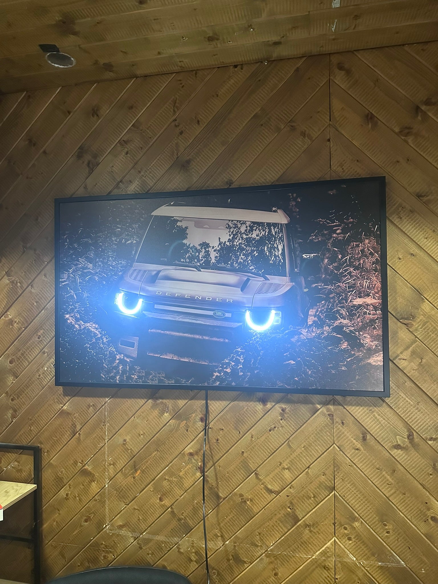 Car on a screen in a room with wooden walls