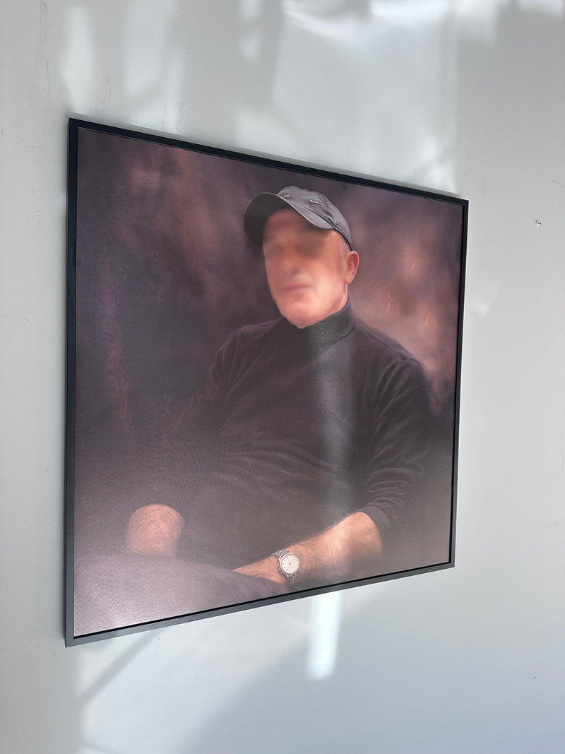 Framed portrait of a man wearing a cap on a white wall.
