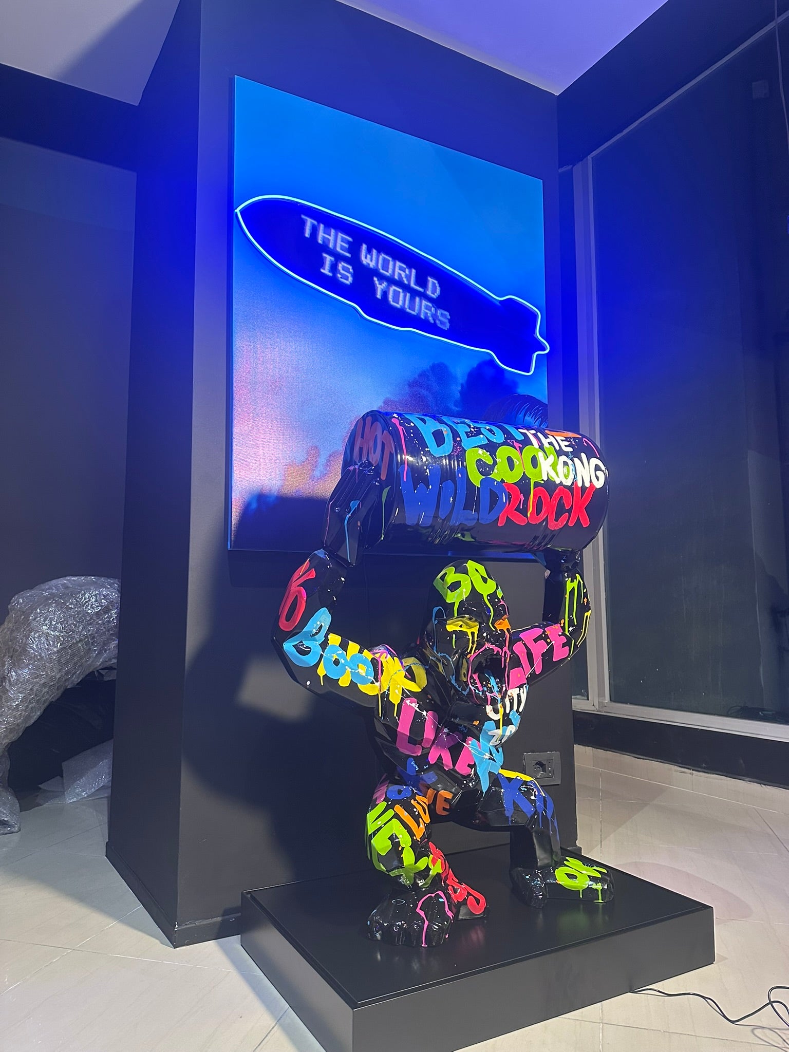 Colorful graffiti gorilla statue holding industrial barrel in modern luxury showroom