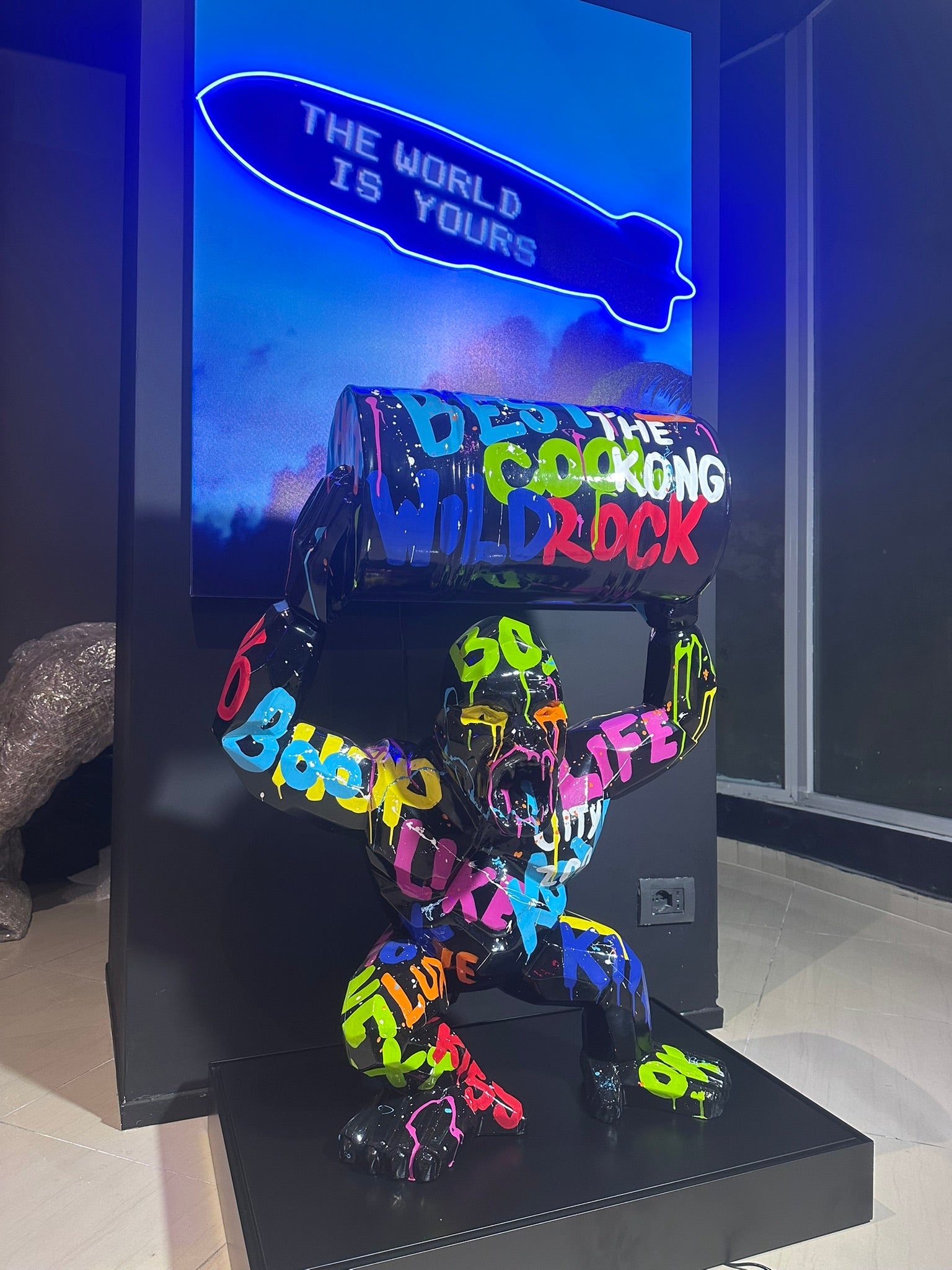 Colorful graffiti gorilla statue holding industrial barrel in modern luxury showroom