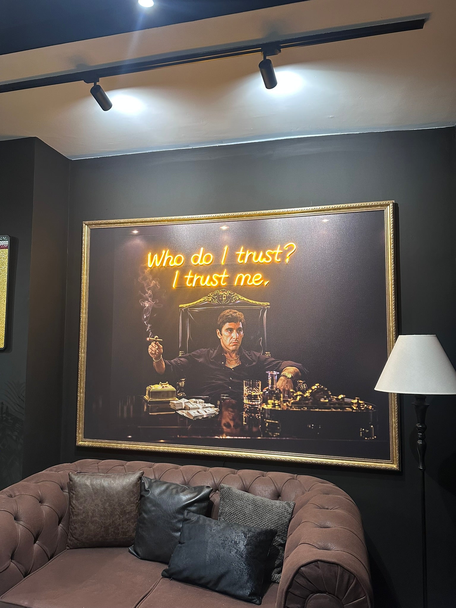 Framed artwork with a quote on a wall above a brown sofa.